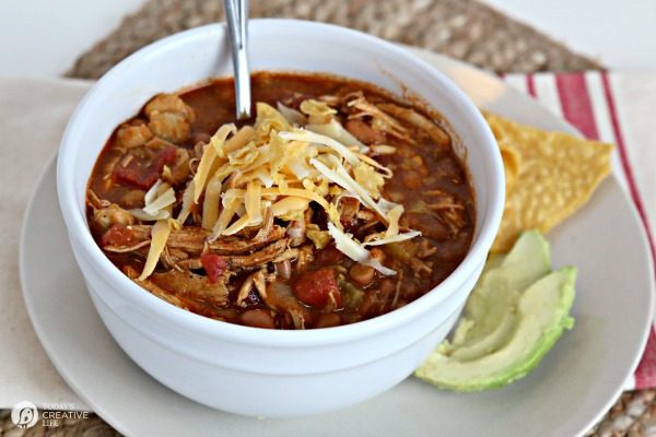 Crockpot Chicken Tortilla Soup in a white bowl with shredded cheese on top. 