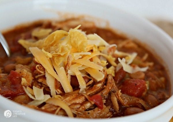 Slow Cooker Chicken Tortilla Soup Recipe in a white bowl with tortilla chips and cheese on top