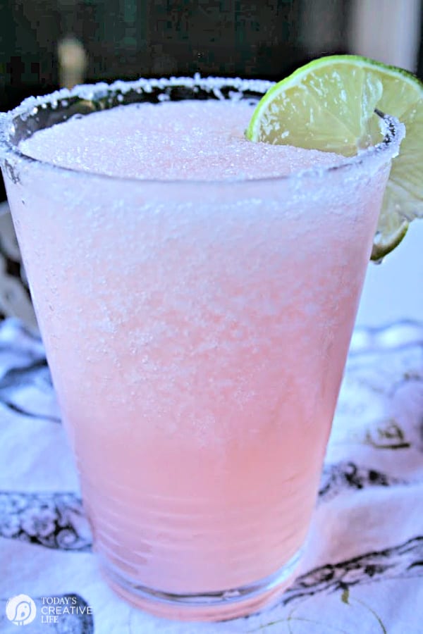 Pink margarita in a glass with a lime garnish