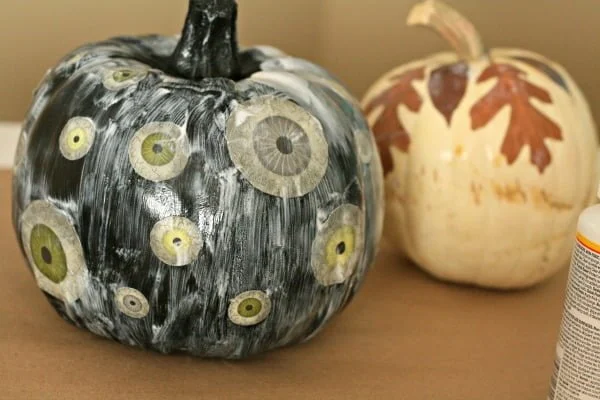 Mod Podge and paper cut outs brushed on pumpkins waiting to dry