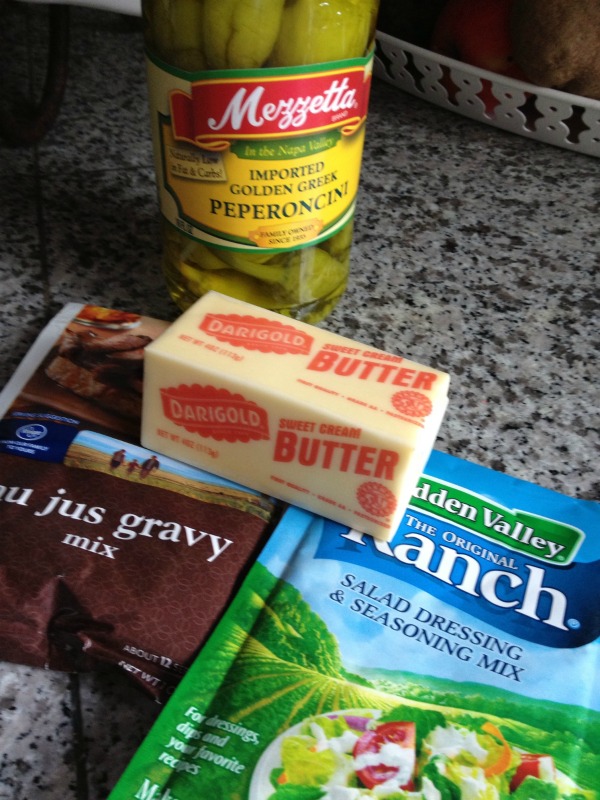 Ingredients for Crockpot Mississippi Pot Roast - Ranch dressing packet, au jus packet, a stick of butter and banana peppers. 