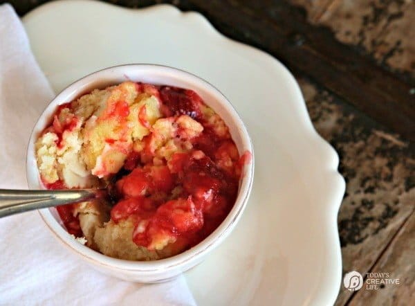 Slow Cooker Strawberry Dump Cake with Pineapple in a white bowl on a white plate. 