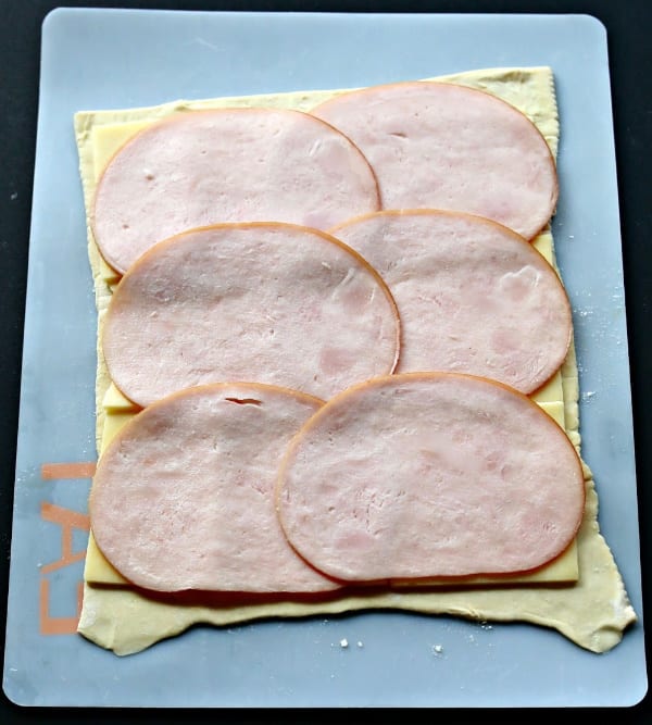 turkey slices lined up over a square piece of puff pastry dough.