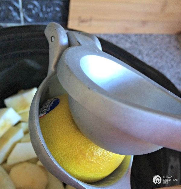 Metal citrus press squeezing a lemon for homemade applesauce.