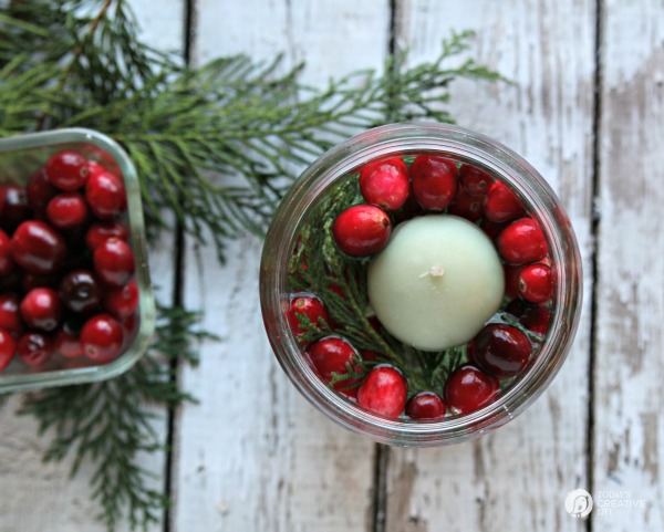 Easy Table Decor for Christmas. Jar filled with water, cedar clippings and cranberries. Add floating candle.