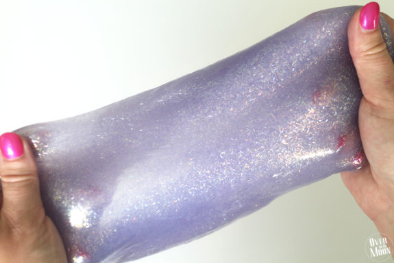 hands stretching purple slime for kids