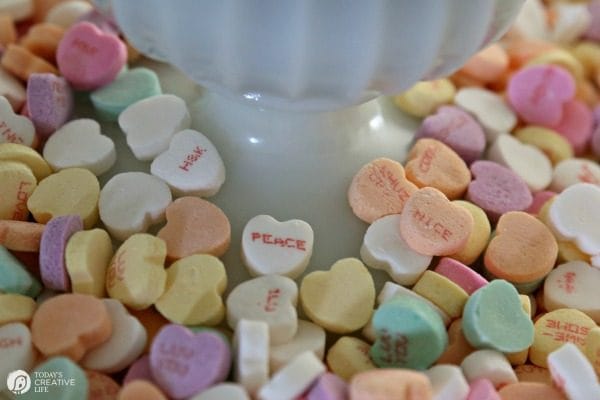 10 Minute Valentines Table Decor | create a quick, simple and easy Valentine's Day decorations tablescape centerpiece with a heart shape doily table runner, conversation hearts and daisies. See more on Today's Creative Life. 