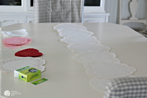 10 Minute Valentines Table Decor | create a quick, simple and easy Valentine's Day decorations tablescape centerpiece with a heart shape doily table runner, conversation hearts and daisies. See more on Today's Creative Life.