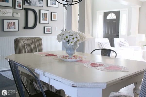 10 Minute Valentines Table Decor | create a quick, simple and easy Valentine's Day decorations tablescape centerpiece with a heart shape doily table runner, conversation hearts and daisies. See more on Today's Creative Life. 