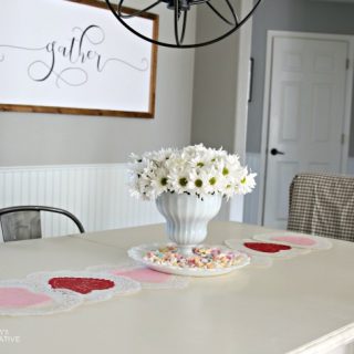 10 Minute Valentines Table Decor | create a quick, simple and easy Valentine's Day decorations tablescape centerpiece with a heart shape doily table runner, conversation hearts and daisies. See more on Today's Creative Life.
