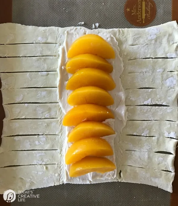 fresh peaches and sweetened cream cheese on a sheet of puff pastry