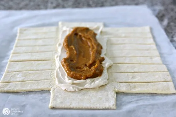 adding a layer of pumpkin filling to a puff pastry braid