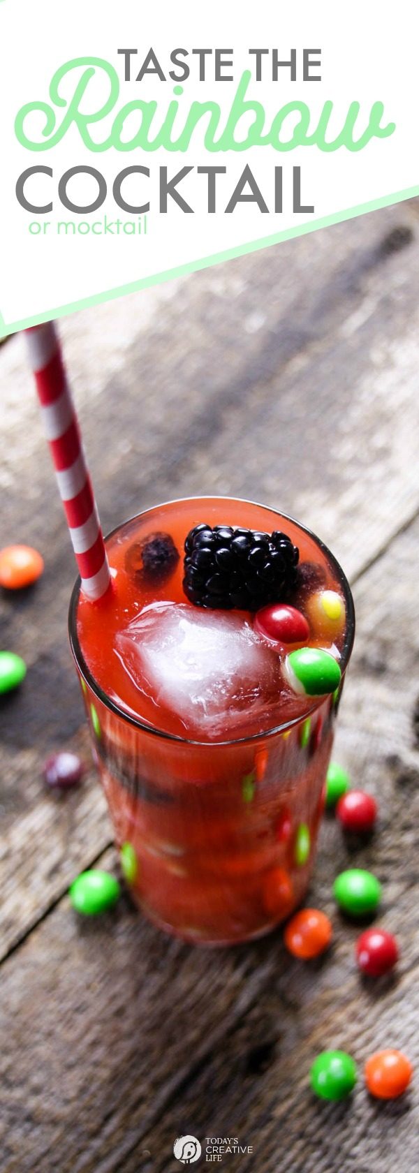 Taste the Rainbow Cocktail Recipe colorful drink in a tall glass with skittles and a blackberry. 