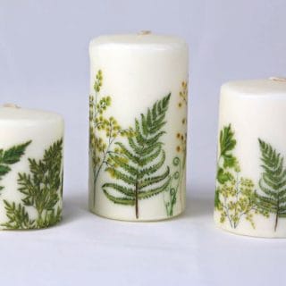 white candles with green ferns on them