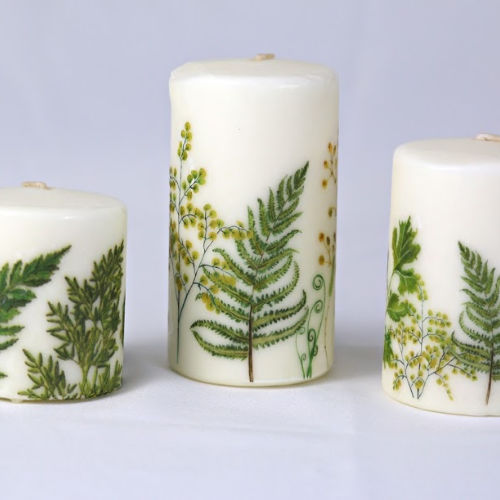 white candles with green ferns on them