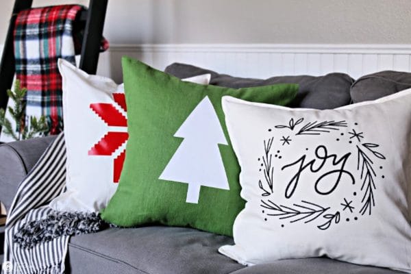 3 holiday themed pillows on sofa.