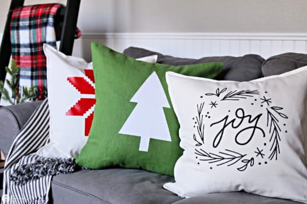 3 holiday themed pillows on sofa.