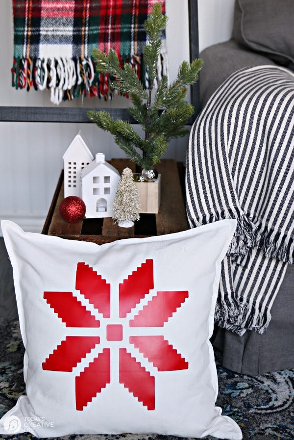 White Pillow with red snowflake sitting on the floor. 