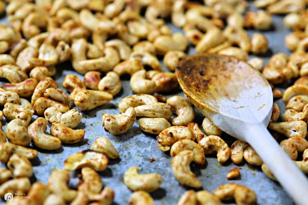 Cashew nuts with wooden spoon on baking pan