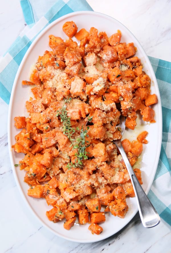 White platter with cubed sweet potatoes, sprinkled with parmesan cheese.