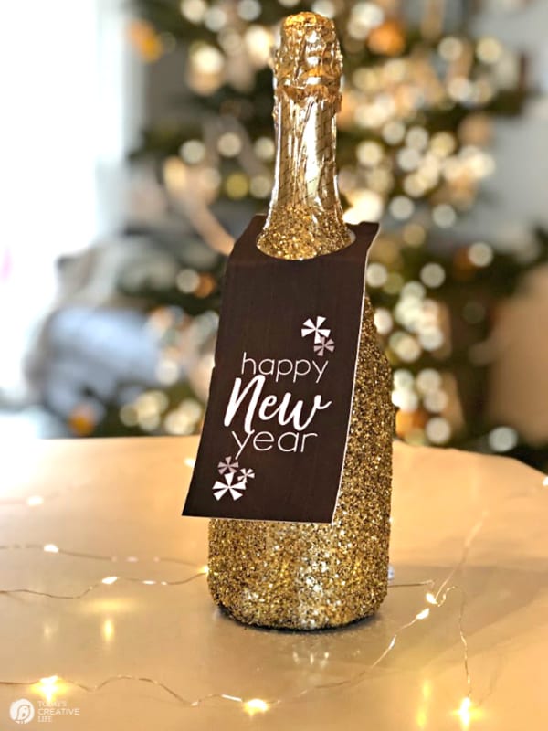 Glittered covered champagne bottle with printable NYE tag