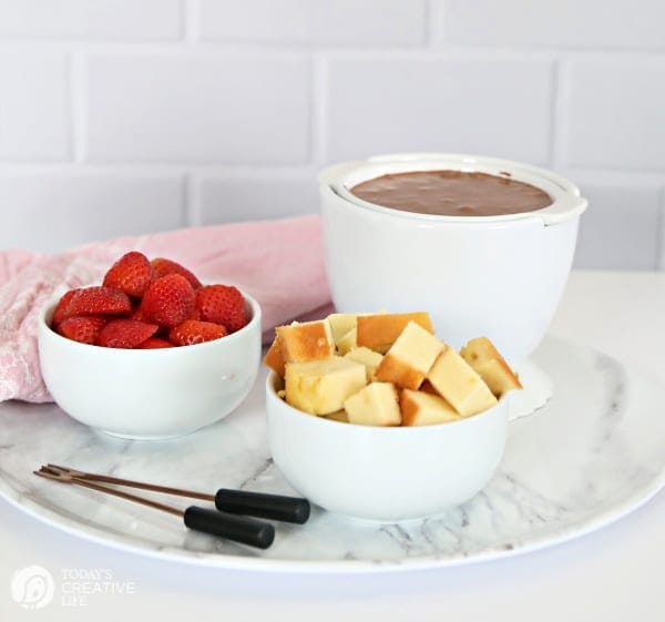 3 white bowls with chocolate fondue and dippers 