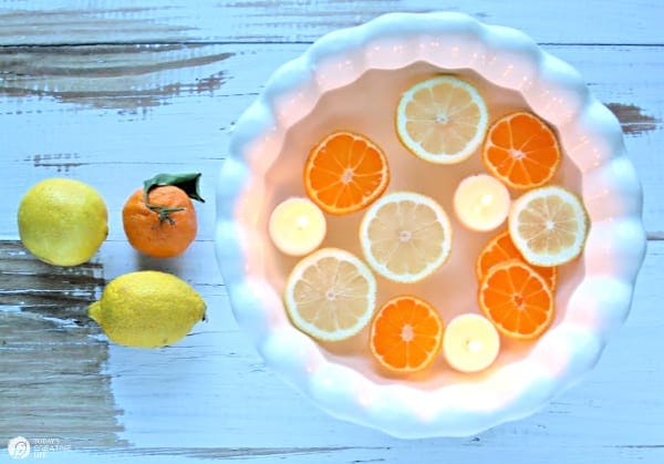 white bowl with floating sliced lemons and floating candles. 