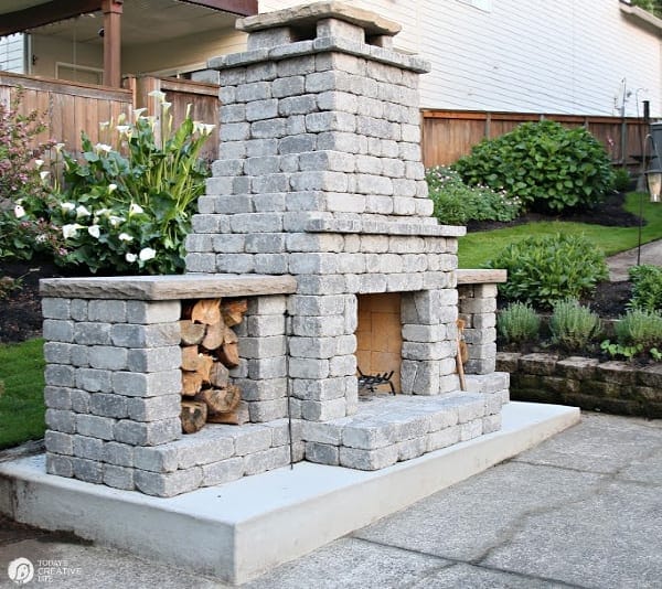 Grey stone backyard fireplace with wood boxes