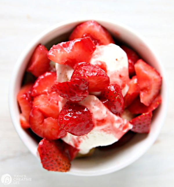 white bowl with strawberries over ice cream