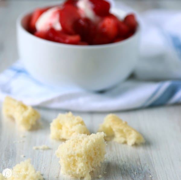 white bowl with strawberries with crumbled cake on counter