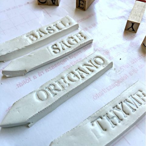 White clay garden plant markers stamped with herb name.