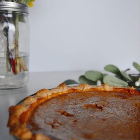 Pumpkin pie on counter with a vase of flowers