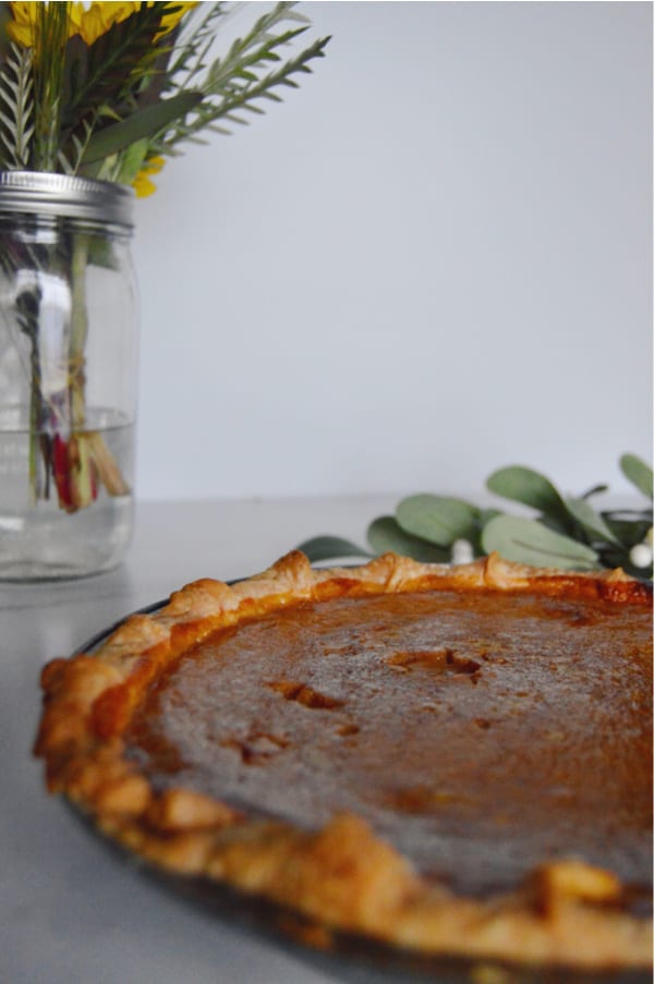 Pumpkin pie on counter with a vase of flowers