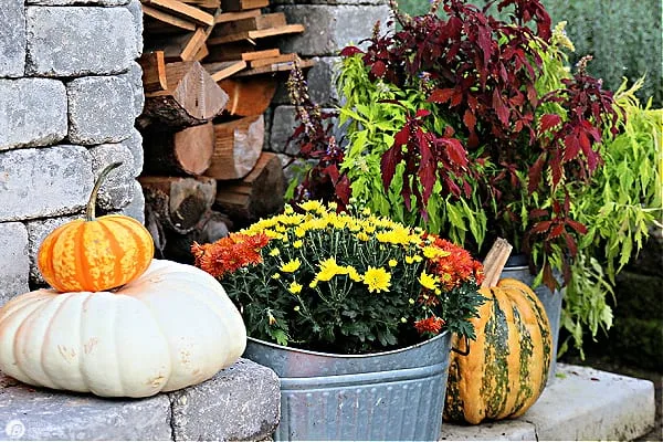 Stacked pumpkins on an outdoor fireplace hearth.