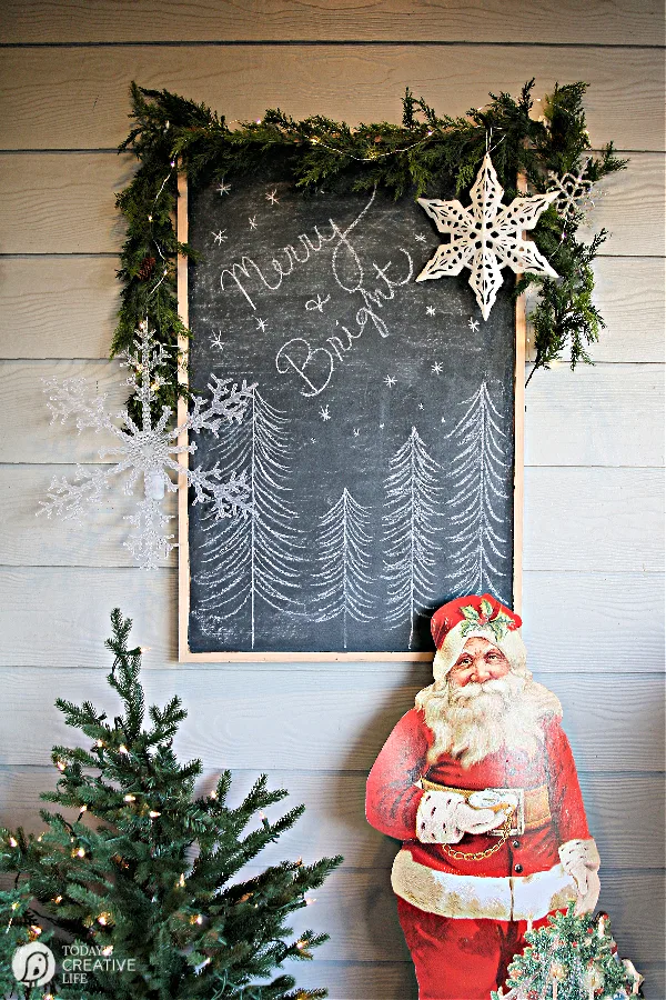 Christmas Porch Decorating Ideas with a vintage cut out of Santa and a holiday sign. 