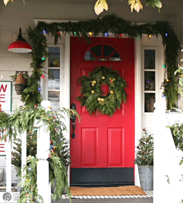 Front porch decorated for Christmas. Red Door with wreath. 