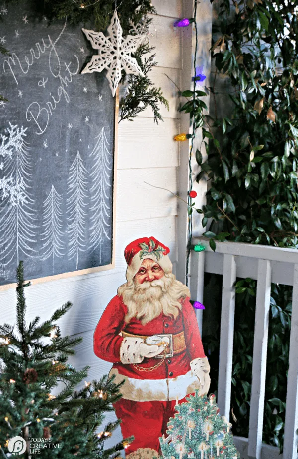 Christmas Porch Decorating Ideas with a vintage santa and small Christmas trees. 