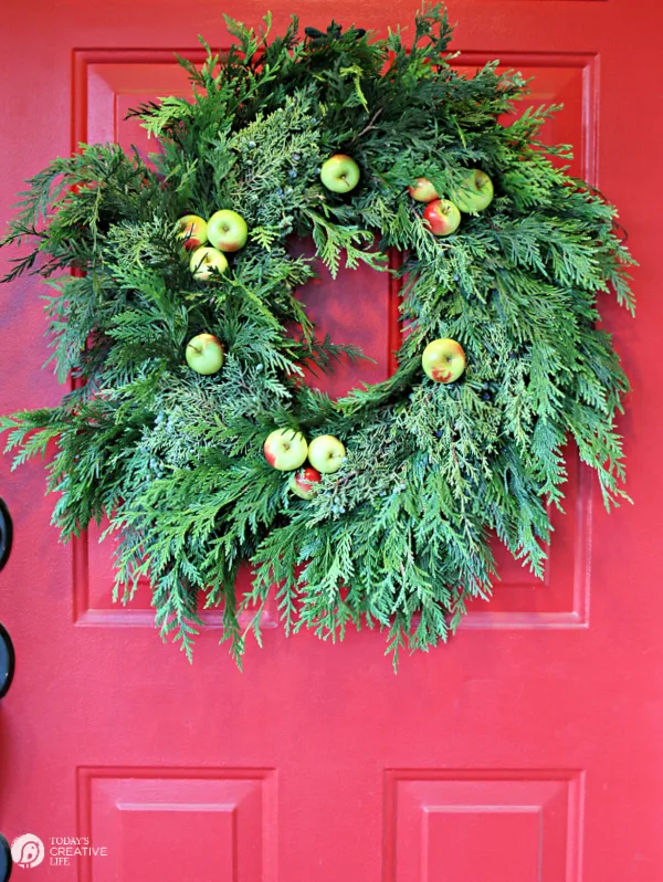 Cedar wreath with apples on a red door. 