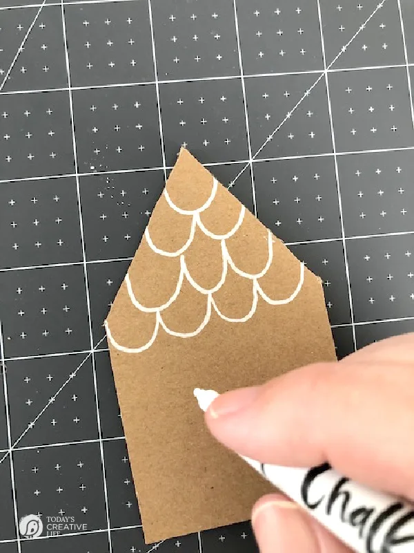 Drawing on a brown paper house with white chalk marker