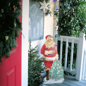 Vintage decorated Christmas Porch with garland and Santa cutout.
