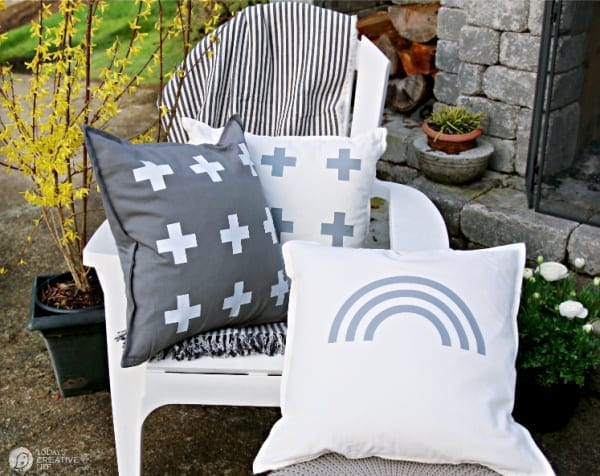 White chair with 3 decorative pillows in grey and white.