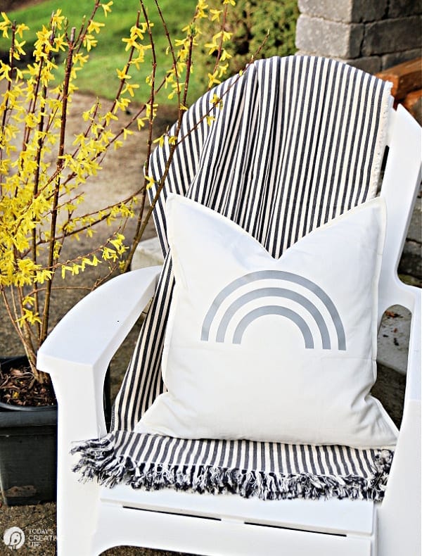 White chair with striped blanket and white rainbow pillow for DIY Patio Ideas. Cricut Maker Iron-on project. 