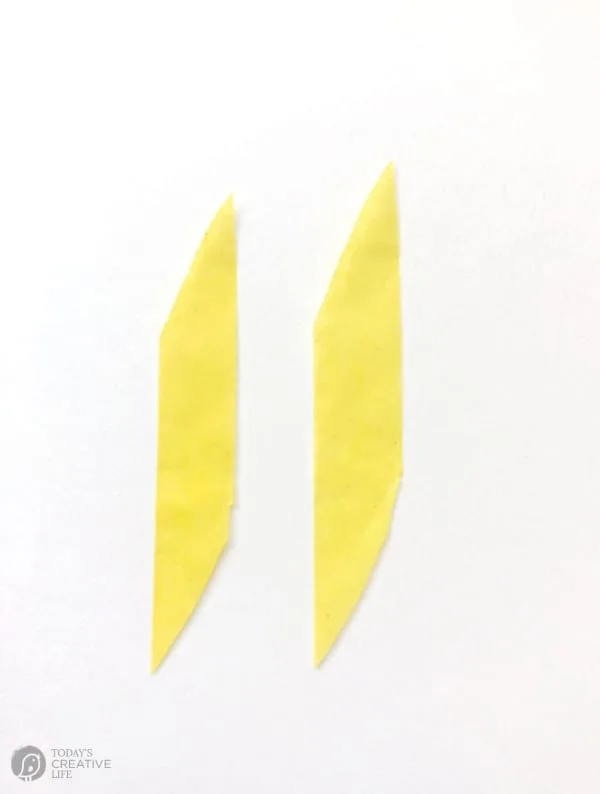 Two small strips of yellow tissue paper for making faux forsythia blooms.