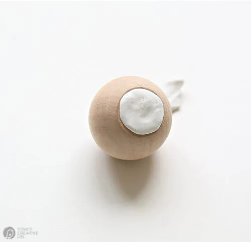 Wood cabinet knob with white putty on the bottom for making a craft project.