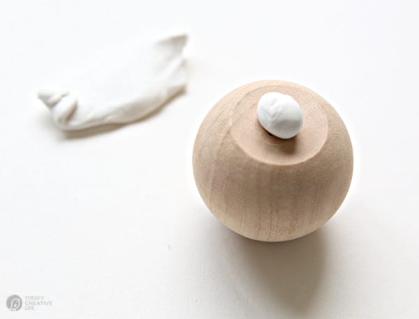 White sugru glue putty on the bottom of a wood knob.