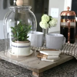 Wood tray on kitchen counter styled with coffee supplies.