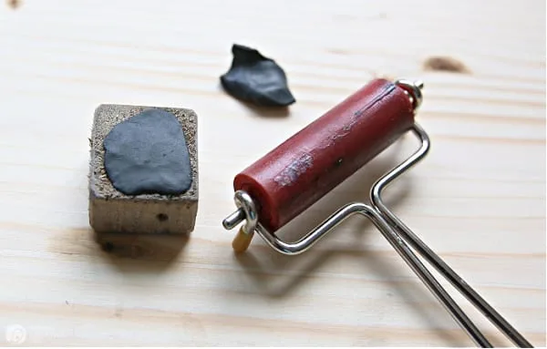 Black Sugru moldable glue spread over a cube of wood to be used for a tray leg.