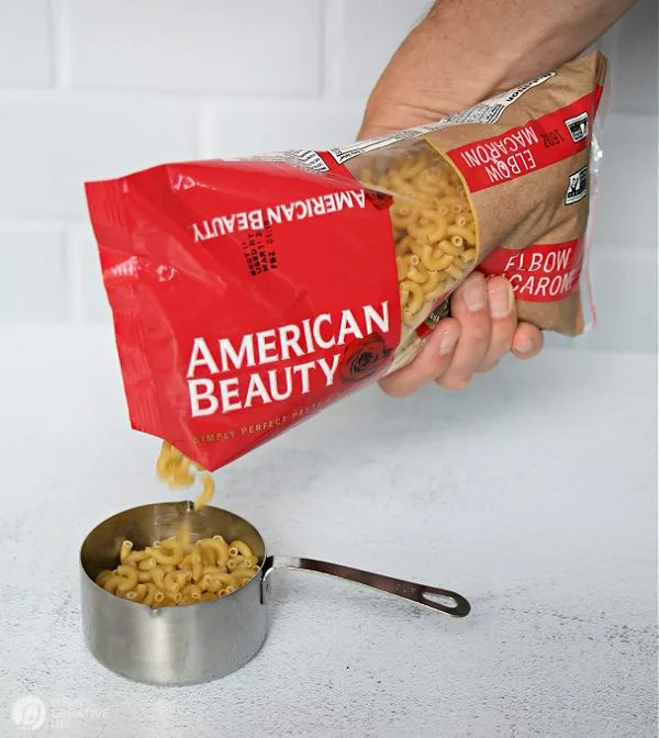 Pouring pasta into measuring cup.