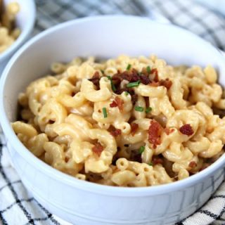 Creamy mac and cheese with bacon and chives served in a white bowl