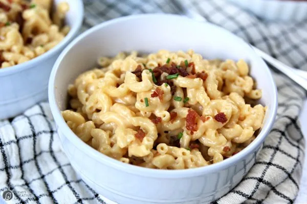 Creamy mac and cheese with bacon and chives served in a white bowl